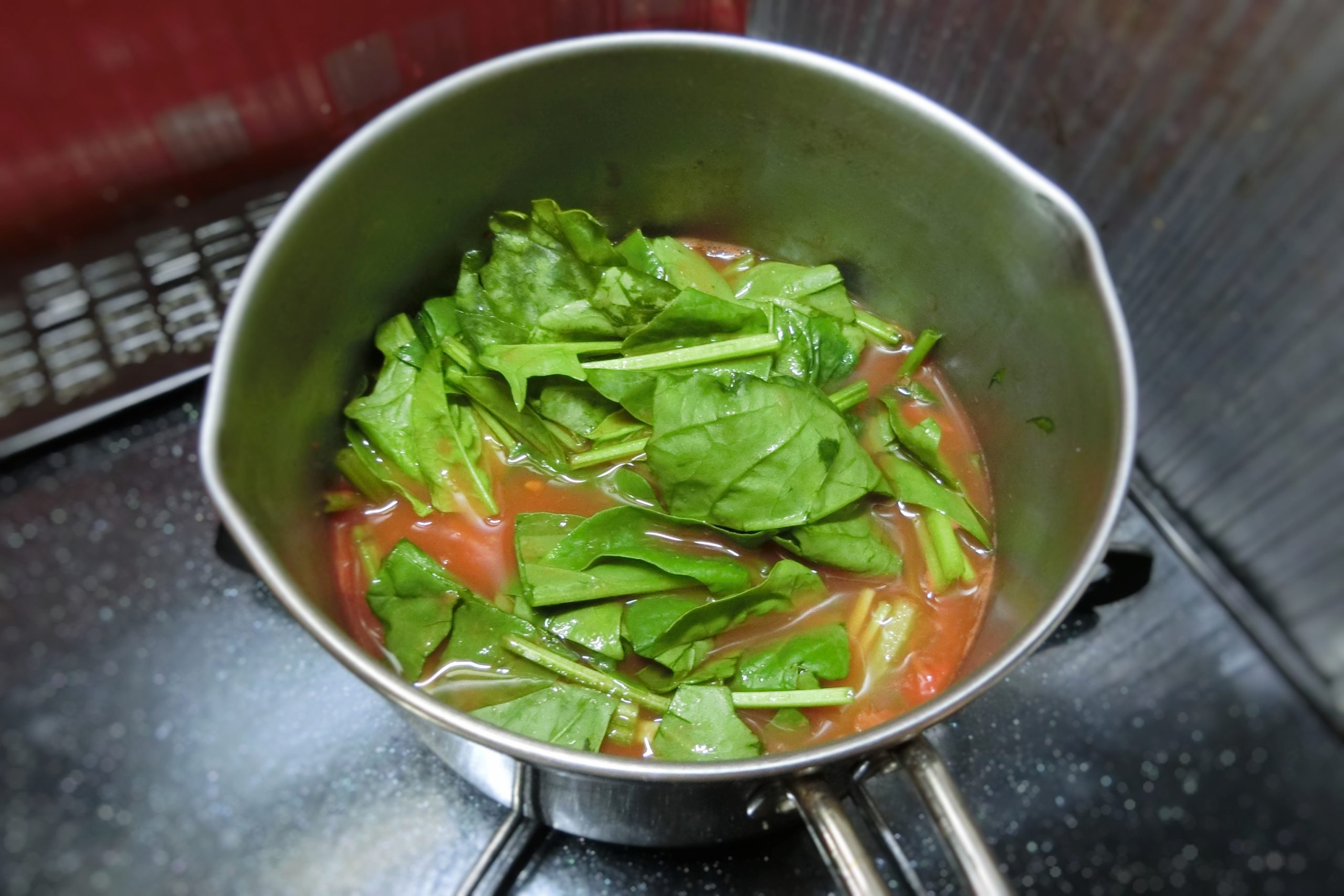 鍋にトマト缶、水を入れて沸騰させたらほうれん草と塩を加える